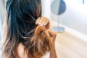 Woman running a comb through damaged hair with split ends